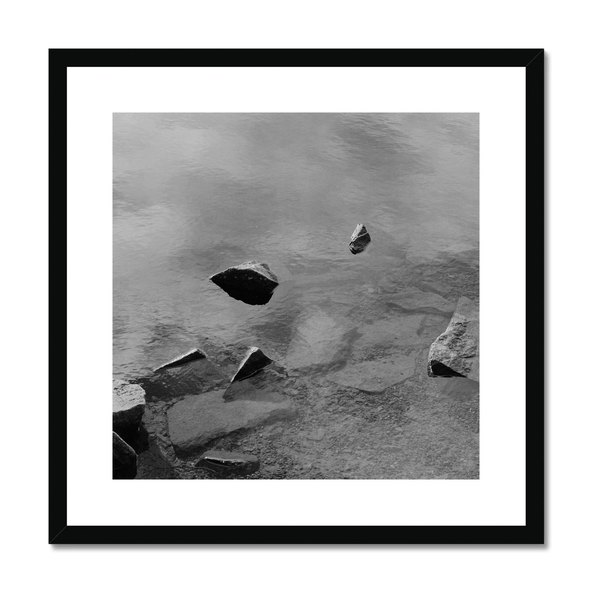 Black and white analog fine art photography print featuring a landscape with a lake and rocks in Norway, wall art in a black handmade wooden frame.