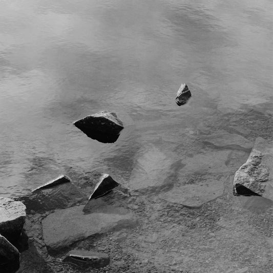Black and white analog fine art photography print featuring a landscape with a lake and rocks in Norway, available as wall art with framing options.