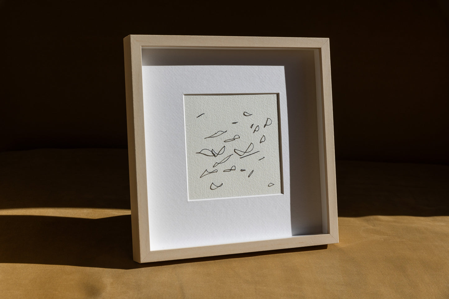 Framed abstract embroidery on paper, an original minimalist relief artwork representing black birds, changing with the light, angled