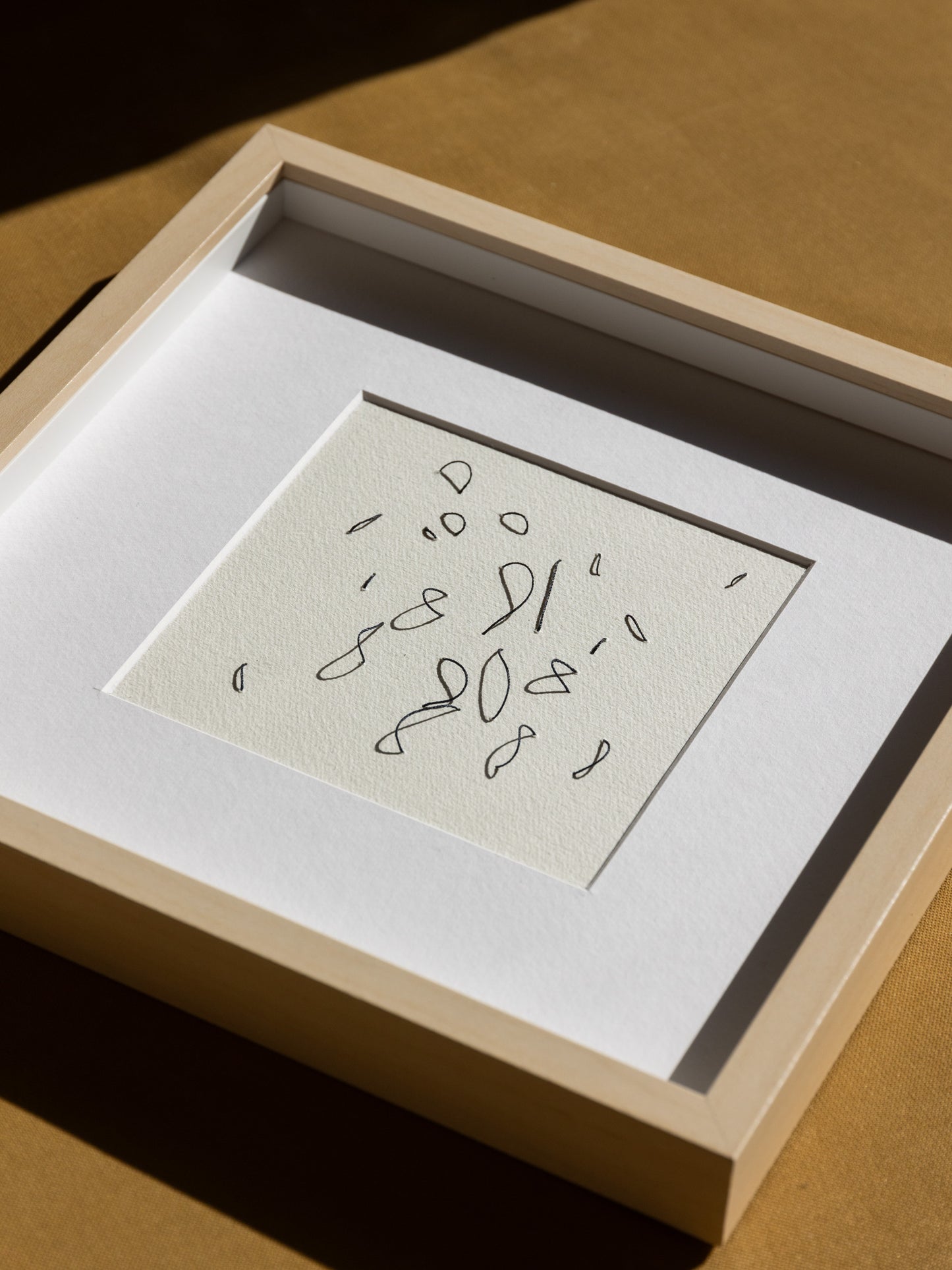 Framed abstract embroidery on paper, an original minimalist relief artwork representing black birds, changing with the light, angled detail