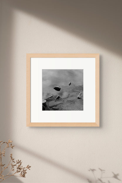Black and white analog fine art photography print featuring a landscape with a lake and rocks in Norway, wall art in a handmade wooden frame. 
