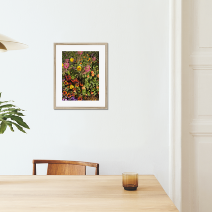 Colorful fine art photography print featuring a vibrant display of flowers, shown in an interior setting in a wooden frame.