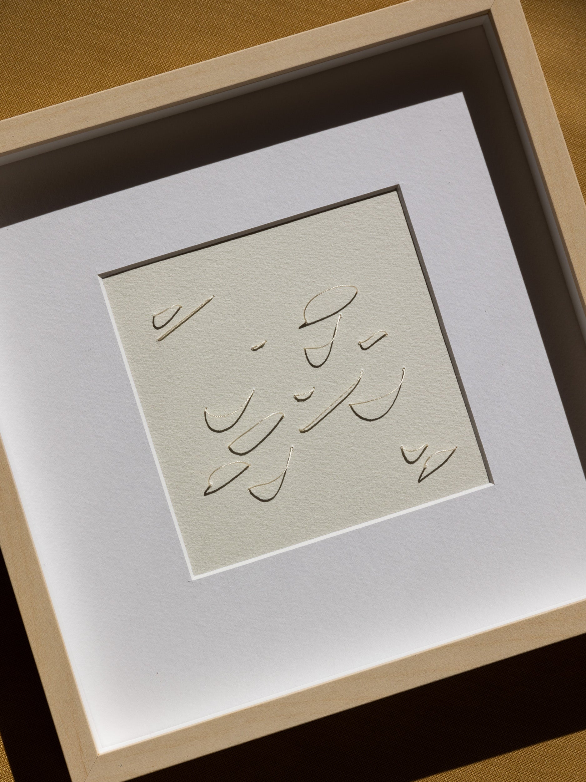 Framed abstract embroidery on paper, an original minimalist relief artwork representing white birds, changing with the light.